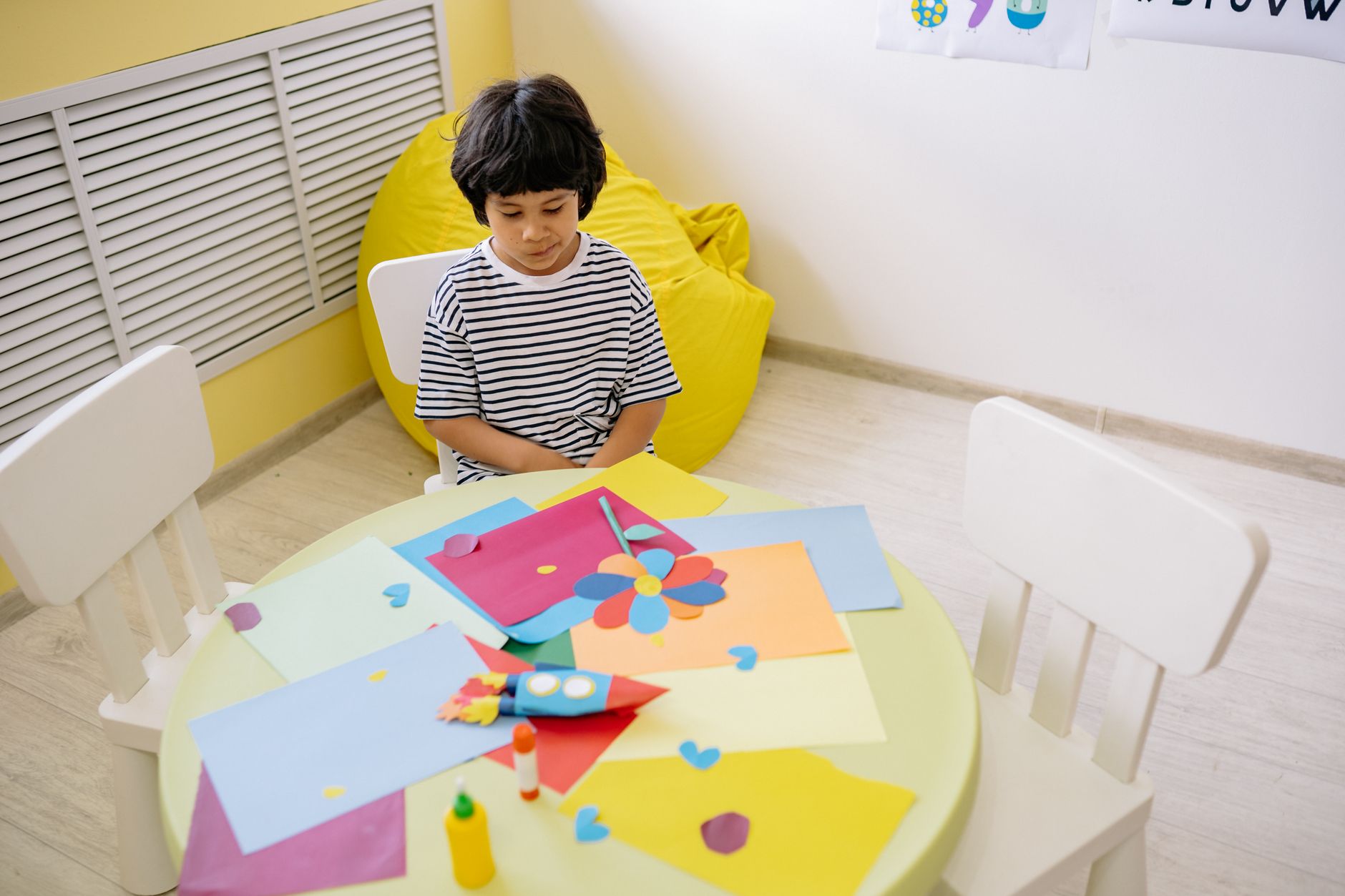 Plate 14. A boy sits alone at a round table surrounded by his own cut-paper shapes.